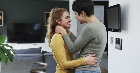 Joyful Lesbian Couple Embracing in Modern Apartment