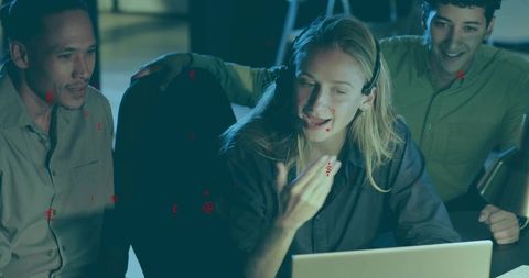 Late-night support team collaborating on customer call with headset, laptop and desk lamp