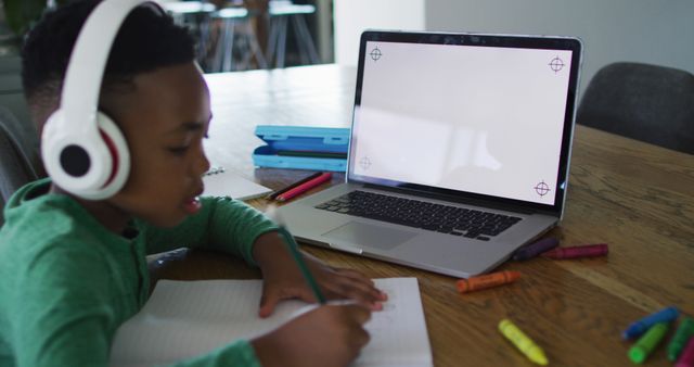 African american boy having a image call on laptop with copy space while doing homework at home. distant learning and online education concept