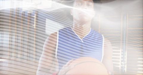 Basketball player holding ball under blinds lighting in indoor gym portrait