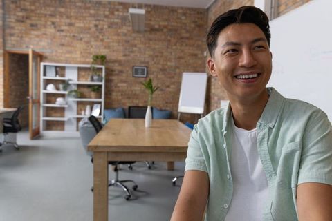 Asian Man Smiling in Modern Minimalist Office Environment