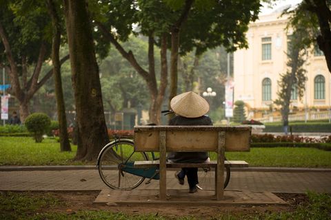 Person in conical hat relaxing on park bench during morning