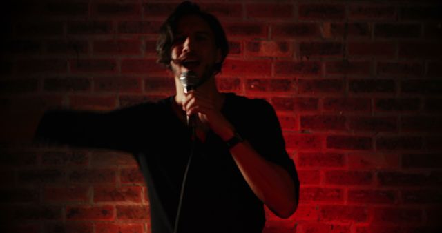 Comedian passionately performing stand-up comedy in a dimly lit venue with a brick wall backdrop. Suitable for marketing comedy clubs, live entertainment, nightlife events, promoting comedic talent or illustrating performance and entertainment concepts.