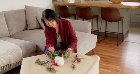 Senior Woman Crafting Handmade Evergreen Wreath at Home