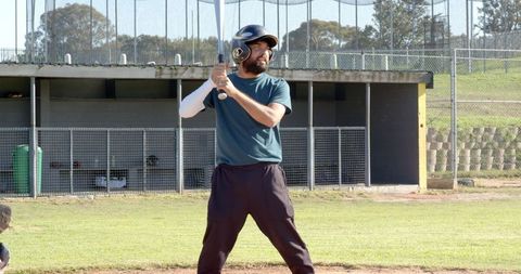 Baseball batter preparing to swing at community field wearing helmet and arm compression