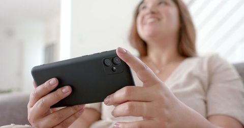 Smiling Woman Relaxing with Mobile Phone in Modern Living Room