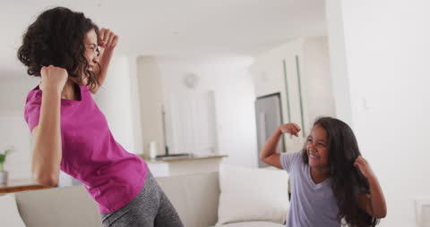 Mother and Daughter Exercising With Laughter at Home