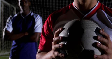 Focused Soccer Player Holding Ball on Darkened Field
