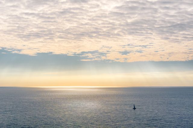 Dawn Over Calm Ocean with Sailboat and Dramatic Clouds - Download Free Stock Photos Pikwizard.com