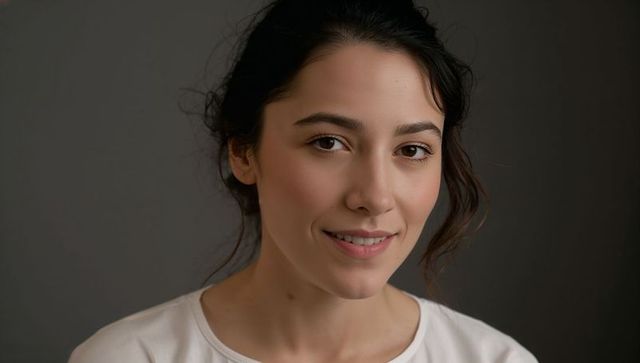 Warm natural headshot of smiling young woman with dark hair and soft studio lighting