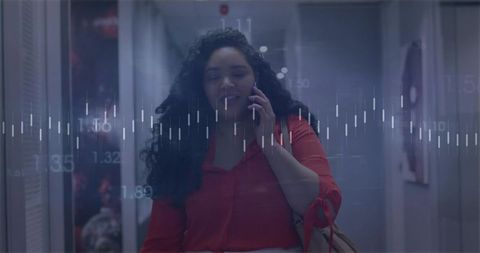 Businesswoman walking and talking on phone with data waveform overlay in modern corridor