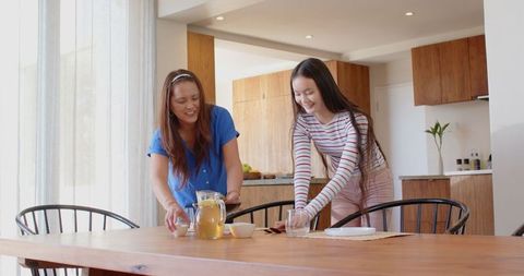 Mother and Daughter Setting Dining Table in Modern Kitchen