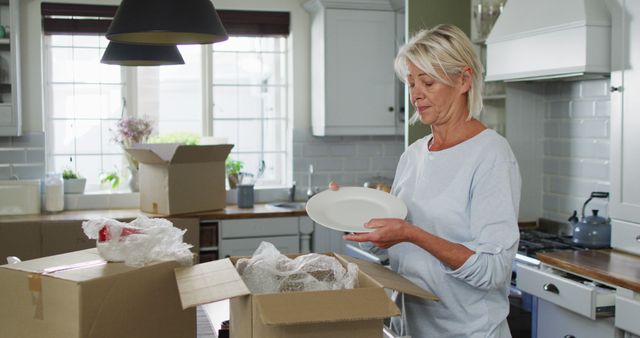 Happy caucasian woman moving house, unpacking boxes in kitchen - Download Free Stock Photos Pikwizard.com