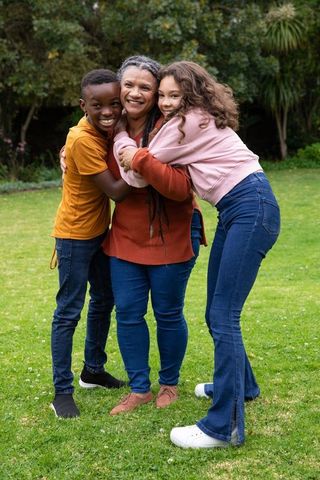 Happy Grandmother with Grandchildren Hugging on Green Lawn