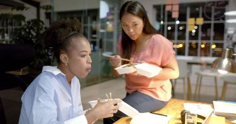 Diverse businesswomen collaborating and enjoying late night meal