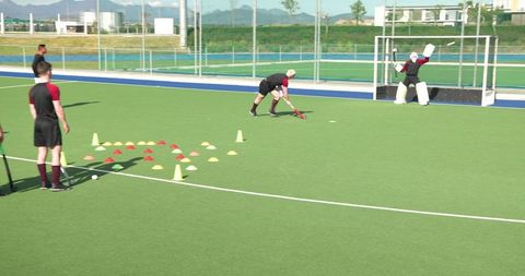 Field hockey players conducting shooting drill in daylight practice