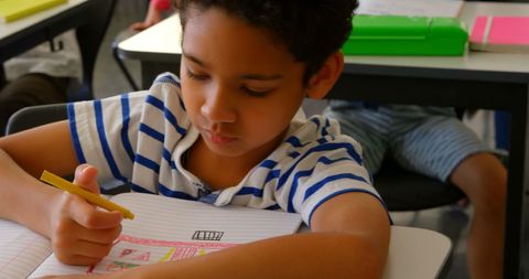 Focused Schoolboy in Striped Shirt Writing in Notebook - Download Free Stock Images Pikwizard.com