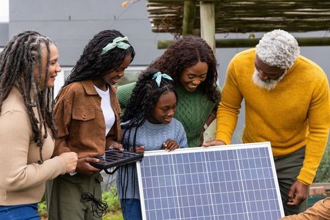 African american multigenerational family exploring solar panel and solar charger outdoors