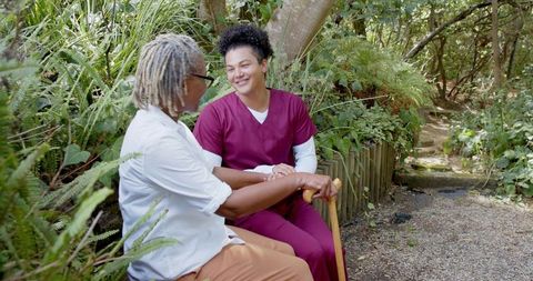 Caregiver comforting elderly woman in tranquil garden setting