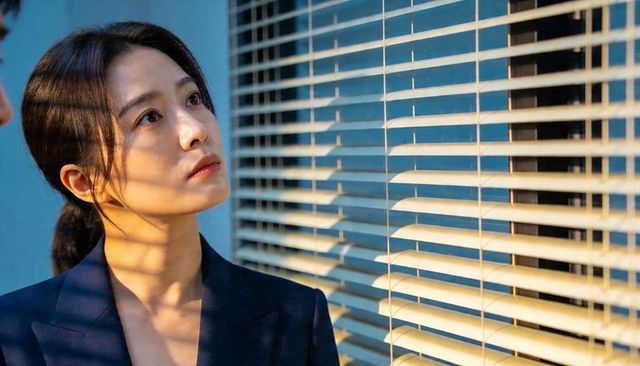 Gazing asian woman in navy blazer by office blinds with cinematic striped light