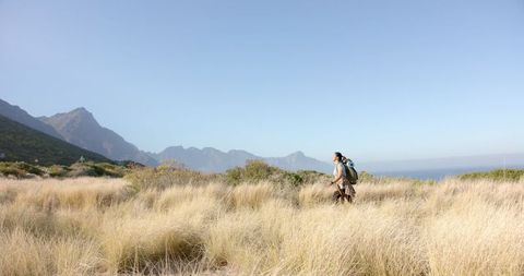Man Hiking with Backpack in Mountainous Grassland