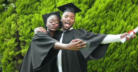 Graduating Students Taking Selfie Outdoors in Caps and Gowns