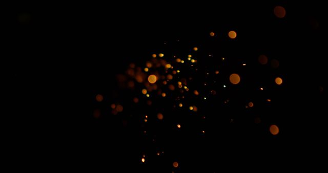 Abstract golden bokeh light sparkles creating a magical and festive atmosphere against a black background. Perfect for use in projects related to celebrations, holidays, night scenes, or decorative purposes.