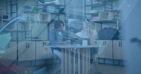 Collaborating over laptop in coworking space with blue digital overlay and teamwork focus