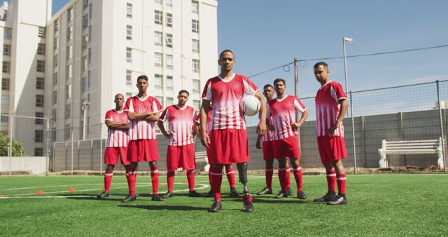 A group of young soccer players standing on an outdoor field, wearing matching red and white uniforms, displaying confidence and teamwork. This image can be used for promoting sports events, illustrating teamwork in sports, or advertising youth athletic programs.