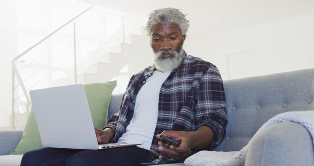 Mature Man Using Smartphone While Working on Laptop at Home - Download Free Stock Images Pikwizard.com