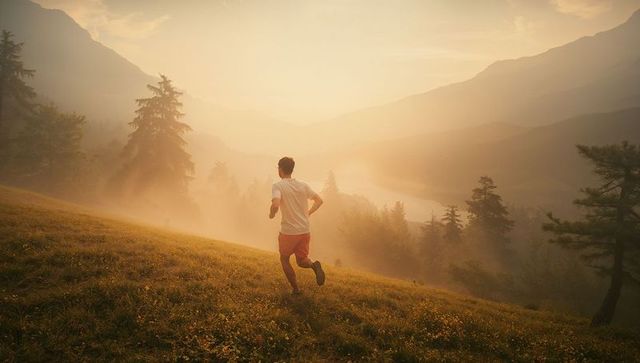 Man running across misty meadow at sunrise, capturing nature's essence