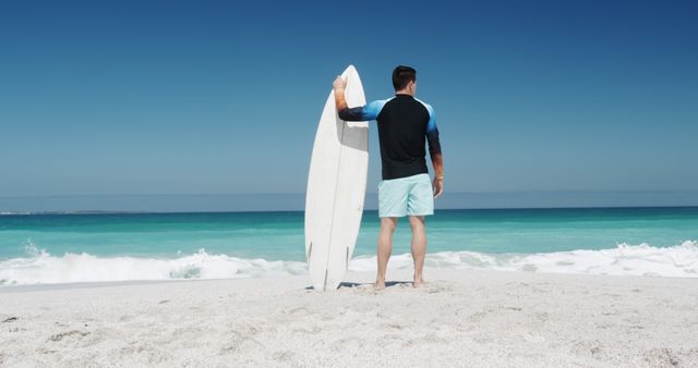 Man Holding Surfboard on Sandy Beach Under Clear Blue Sky - Download Free Stock Images Pikwizard.com