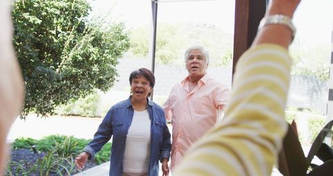 Senior Couple Welcoming Visitors Outside Home