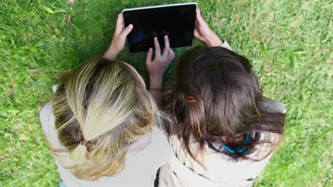Friends Enjoying Tablet Outdoors on Grass