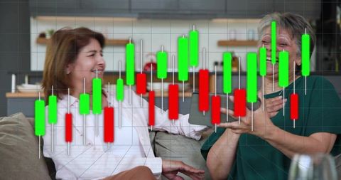 Laughing mature women sharing trading wins on sofa with green and red candlestick chart
