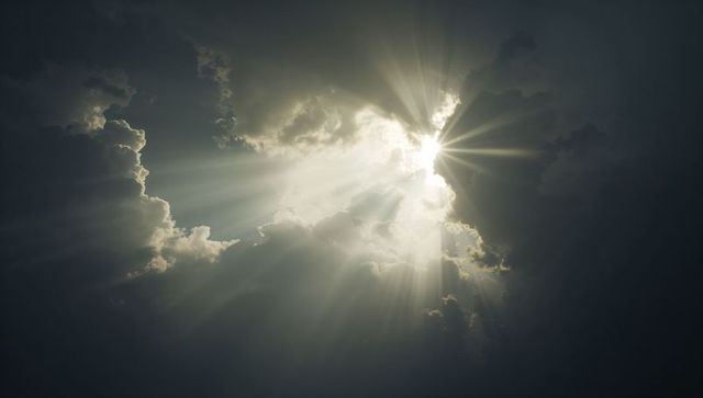 Sunburst breaking through storm clouds, dramatic crepuscular rays and silver linings
