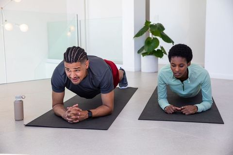 Diverse Couple Performing Yoga Planks in Home Workout Space
