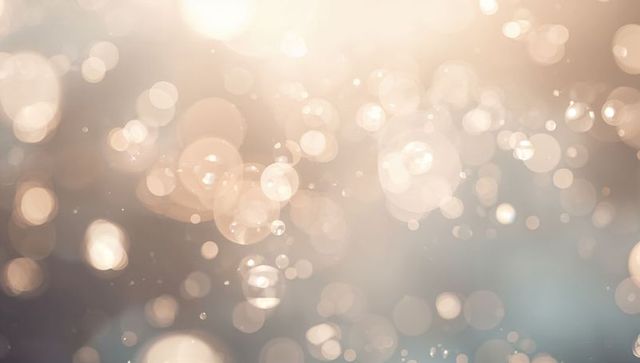 Soft champagne bokeh glow with floating light orbs and warm lens flare