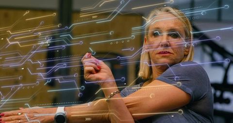 Senior woman demonstrating augmented reality interface with stylus and smartwatch