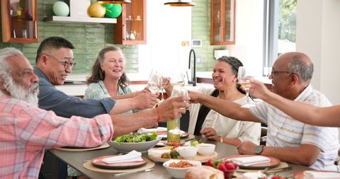 Senior Friends Celebrating with Toast in Modern Kitchen