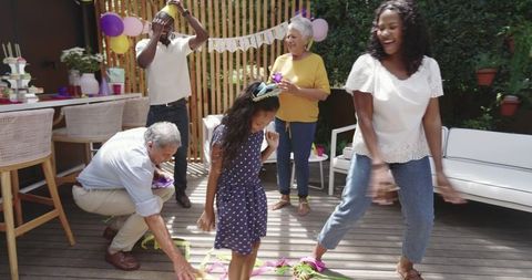 Multigenerational Family Celebrating Outdoors Dancing with Colorful Streamers and Balloons