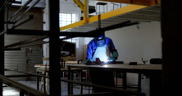 Welder at work in an industrial setting. Skilled laborer is focused on welding in a workshop environment, showcasing craftsmanship.