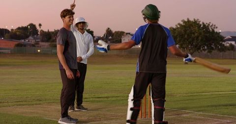 Evening cricket appeal celebrating at crease by diverse friends on suburban pitch