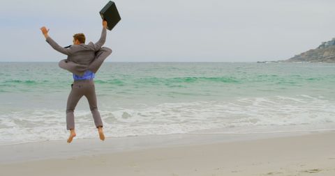 Excited Businessman Jumping for Joy by the Ocean