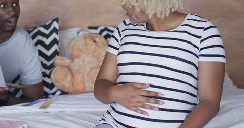 Expecting Couple Shopping Online for Baby Clothes at Home