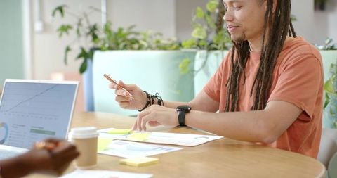 African american man with dreadlocks reviewing charts and collaborating in coworking space