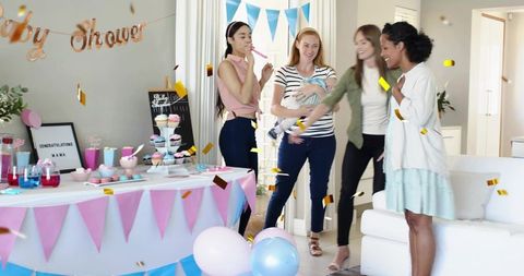 Group celebrating baby shower at home with mother holding newborn and colorful decorations