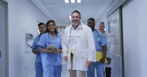 Multidisciplinary medical team walking hospital corridor holding charts and tablets