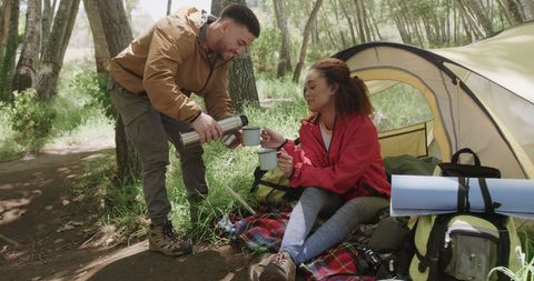 Diverse Couple Enjoying Coffee Outside Tent in Forest