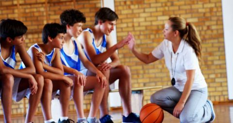 Teen basketball team receiving encouragement from female coach